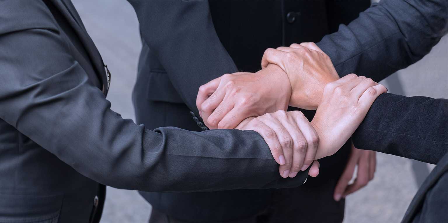 Les 4 Piliers d'une Production Vidéo de Qualité - 4 business men se donnent la main.
