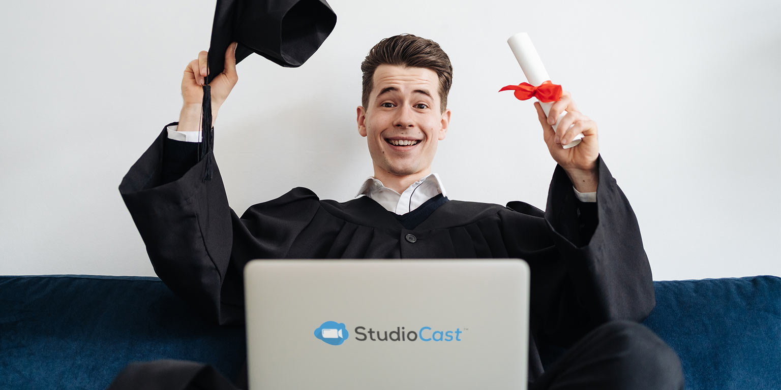 jeune homme assis sur le divan qui assiste à une graduation virtuelle devant sont portable