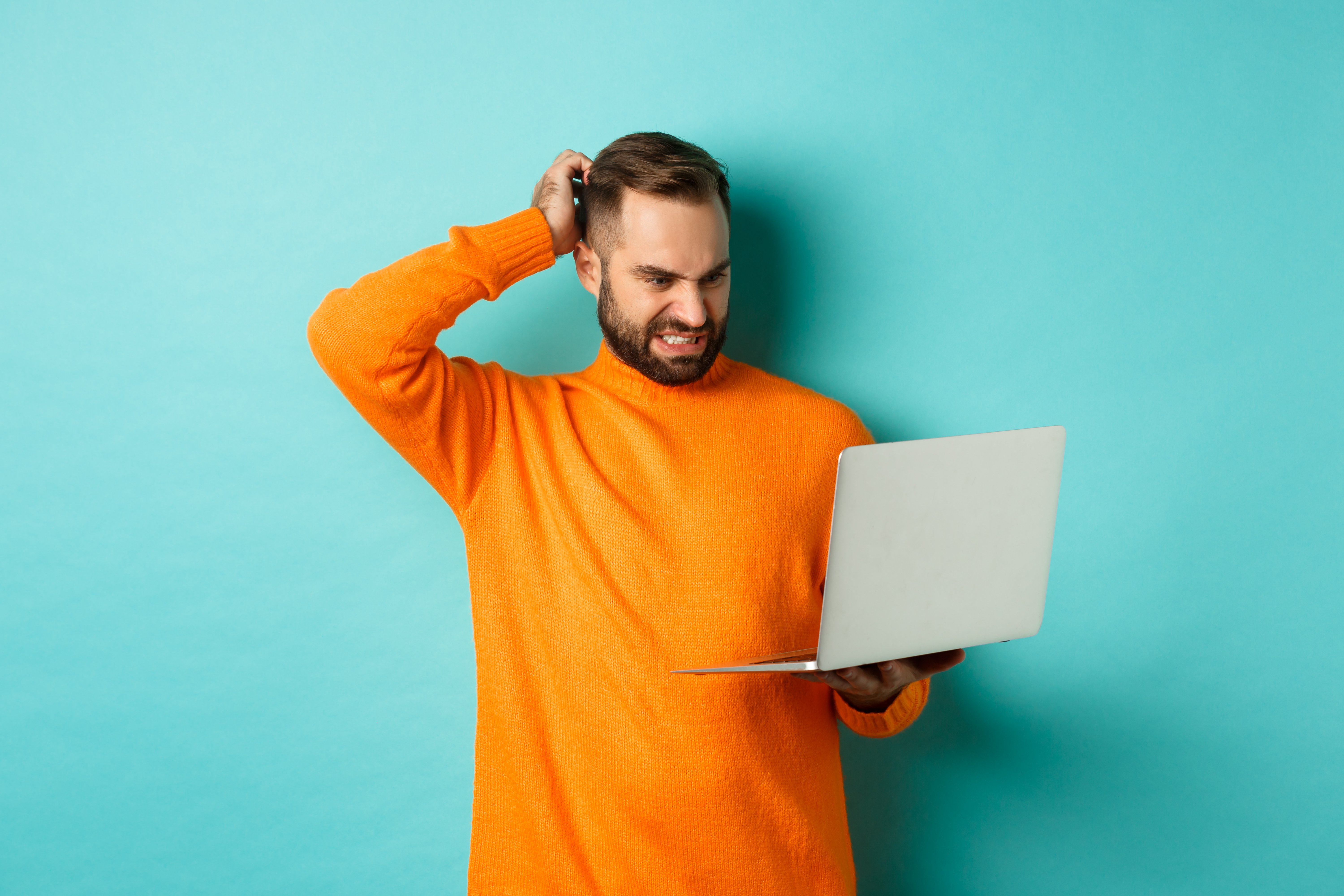 webinaires de formation- Un homme qui regarde un laptop confus sur un background bleu. 
